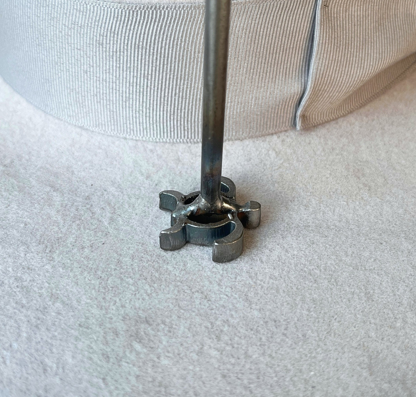 A close-up of a mini branding iron pressed onto the brim of a felt cowboy hat. 