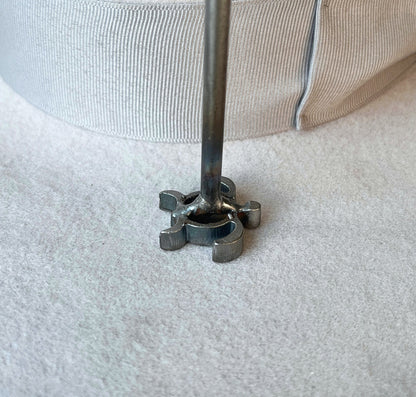 A close-up of a mini branding iron pressed onto the brim of a felt cowboy hat. 