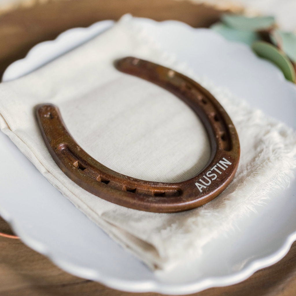 Horseshoe with 'AUSTIN' engraved on a white plate with greenery in the background